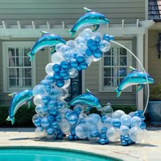 blue and white balloons floating in the air next to a pool with dolphins on it