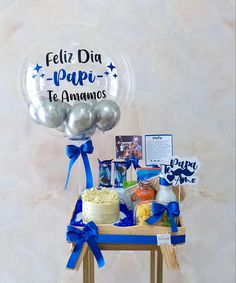 a table topped with balloons and cake next to a sign that says feliz dia papi te amamos