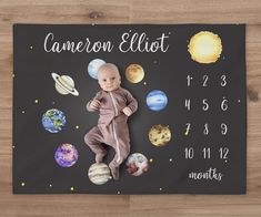 a baby laying on top of a black board with planets