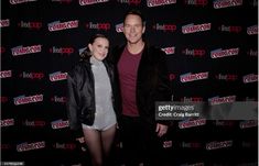 a man and woman standing next to each other in front of a red carpeted wall