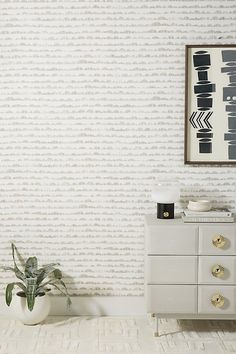 a white dresser sitting next to a wall with a painting on it's side