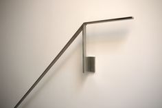 a metal object hanging from the side of a white wall next to a wooden pole