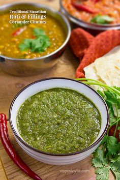 two bowls filled with green salsa next to some tortilla chips and red peppers