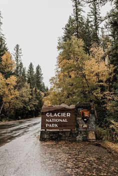 the sign for glacier national park is in front of trees with yellow and orange leaves