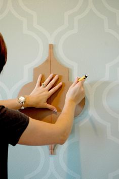 a woman is working on a wall decoration