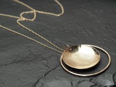 This simple, modern pendant necklace features a 1.25 inch (30mm) diameter hammered and domed 14k gold fill disc floating within a 1.5 inch (40mm) diameter hammered 14k gold fill circle outline. If you choose one of the longer chains (32-36 inches) you can wear the chain at its full length or double it through the bail for a seemingly thicker looking chain at a comfortably shorter length (16-18 inches respectively). All the metalwork is made by me using traditional metalsmithing techniques. If this is a gift? All my pieces come ready for gift-giving- Your piece will come in a gift box. I am happy to include a personalized note- Just write a brief (1-2 sentence) message in 'notes to seller' upon checkout and I will handwrite it on a little note card. A note about what to expect with shipping Circle Outline, Metal Circle, Jewelry Minimalist, Hammered Gold, Modern Pendant, Gold Chain Necklace, Circle Pendant, Minimalist Jewelry, Gold Chain