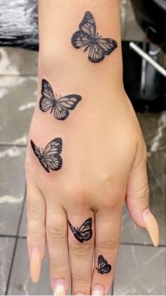 a woman's hand with black butterflies on her left wrist and the other arm