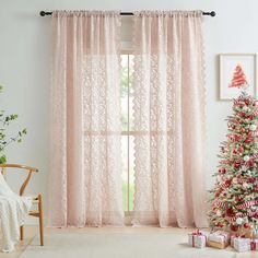 a living room with a christmas tree and pink curtains