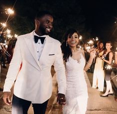 a newly married couple holding sparklers in their hands as they walk down the street