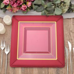 a place setting with pink flowers and silverware on a wooden tableclothed surface