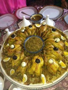 an elaborately decorated dish on a table with plates and silver wares around it