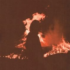 a person standing in front of a fire with lots of flames coming out of it