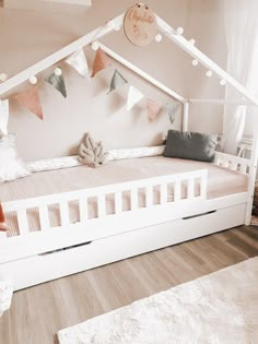 a child's bed made out of white wood with pink and gray decorations on the wall