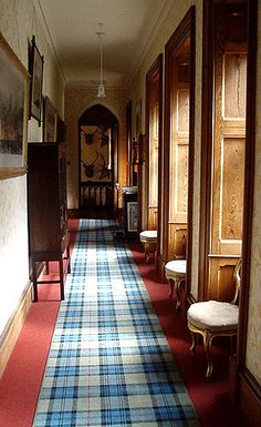 the hallway is lined with wooden paneled doors and plaid rugs on either side