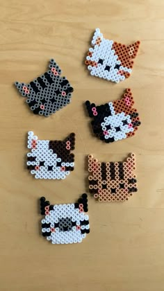 six perler bead cats on a wooden table with one black cat and the other white cat