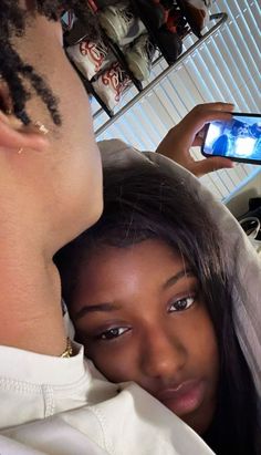 a man taking a photo of a woman with her cell phone while she is getting her hair done