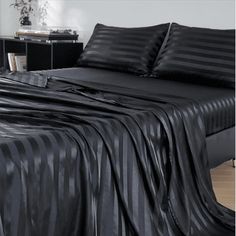 a bed covered in black sheets and pillows