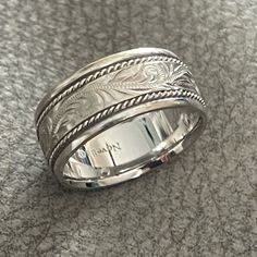 a wedding ring with an intricate design on the inside and outside, sitting on top of a carpeted surface