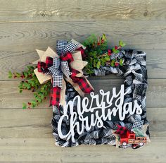 a christmas wreath with the words merry christmas on it and a red truck sitting in front of it