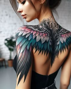 the back of a woman's body with tattoos on her shoulder and wings painted on it