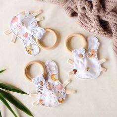 three baby bibs are laying next to each other on a white surface with green leaves