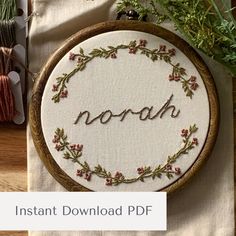 an embroidered hoop with the word noah written in cursive font and surrounded by flowers