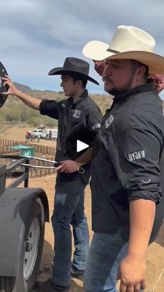 two men standing next to each other in front of a truck with an antenna on it