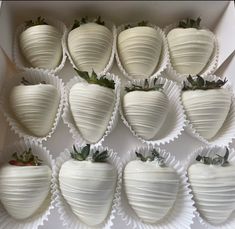 a box filled with white chocolate covered strawberries next to each other on top of a table