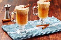 two mugs filled with cinnamon sitting on top of a wooden table