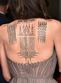 the back of a woman's dress with tattoos on her upper and lower back