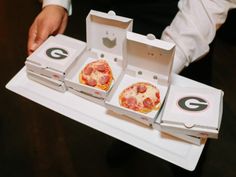 the man is holding three pizzas in boxes on top of each other, one with pepperoni and cheese