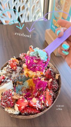 a bowl filled with ice cream and toppings on top of a wooden table next to a book