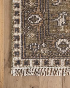 a brown and white rug with fringes on top of wooden floor next to wall