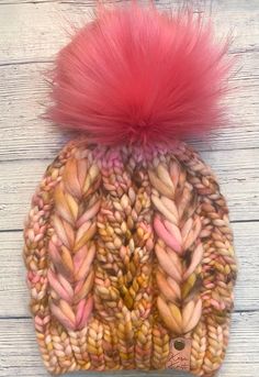 a knitted hat with pink fur pom