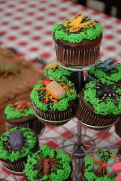 cupcakes with green frosting are stacked on a cake stand and decorated with decorations