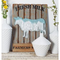 three white vases sitting next to each other on a shelf with a wooden sign that says fresh milk