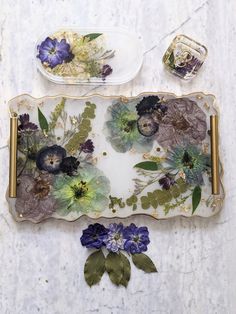 two plates with flowers on them sitting next to each other, one is empty and the other has purple flowers