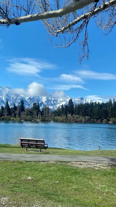 a park bench sitting next to a lake with mountains in the background