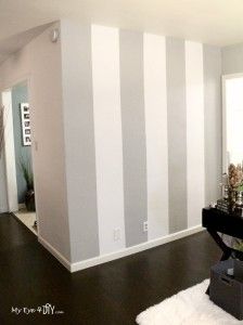 a living room with white and gray striped walls on the wall, hardwood flooring