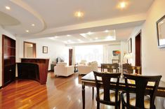 an empty living room and dining area with hard wood flooring, white walls and ceiling lights