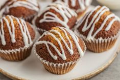 a white plate topped with muffins covered in icing on top of a table