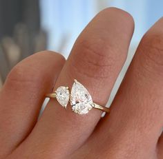 a woman's hand with two pear shaped diamond rings on top of her finger