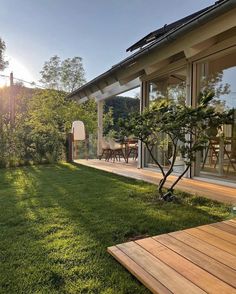 the back yard has grass and wooden decking, with an outdoor dining area in the background