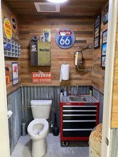 a bathroom with a white toilet sitting next to a red tool box and other items on the wall