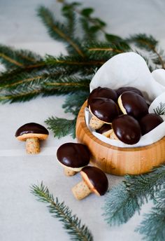 chocolate covered cookies in a wooden bowl surrounded by pine branches