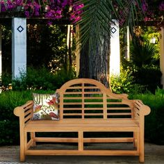 a wooden bench sitting next to a tree with purple flowers hanging from it's branches