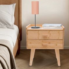 a nightstand with a lamp on it next to a bed