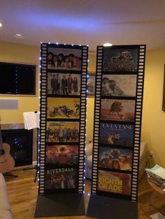 two tall black and white movie posters in front of a fireplace with blue lights on them