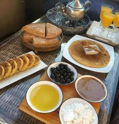 a table topped with plates of food next to glasses of orange juice and cups of tea