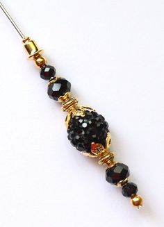 a black and gold beaded necklace on a white surface with an arrow in the middle